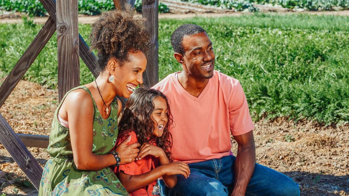Smiling mother, father and daughter laughing together outdoors