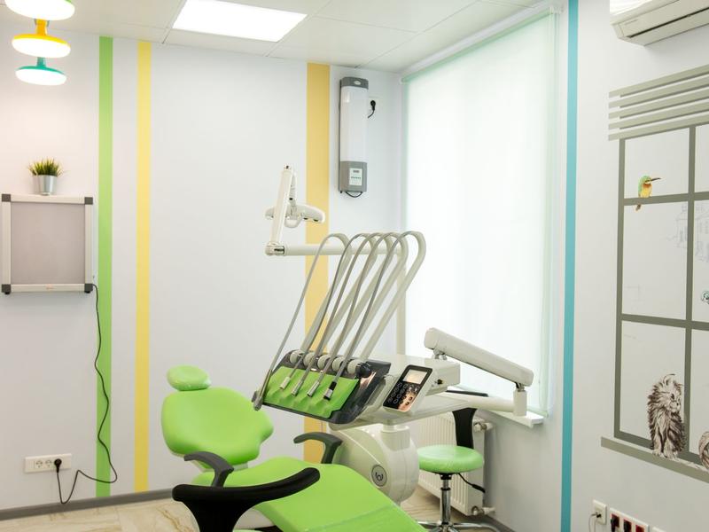 Cheerful dental operatory with a green treatment chair, large window and colorful accent stripes