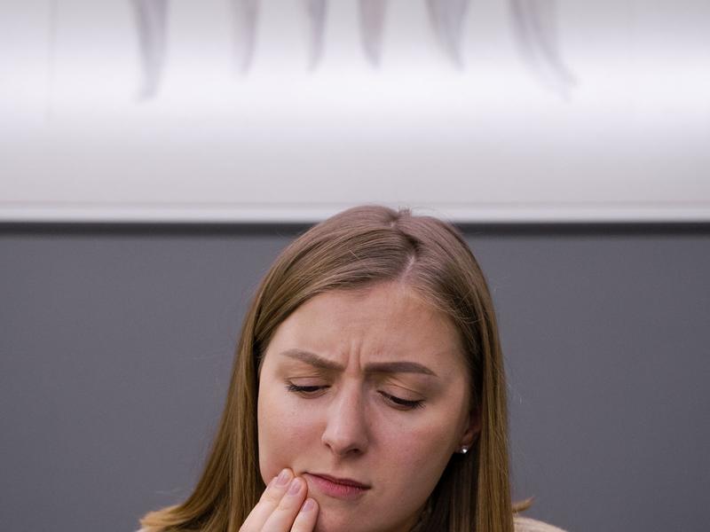 Woman holding her cheek in discomfort from a toothache