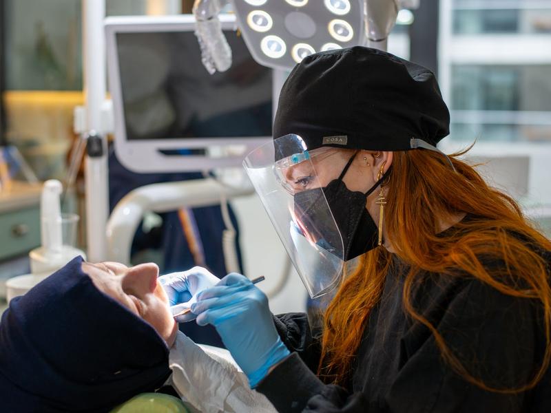 Dentist in protective gear examining a patient in a modern clinic