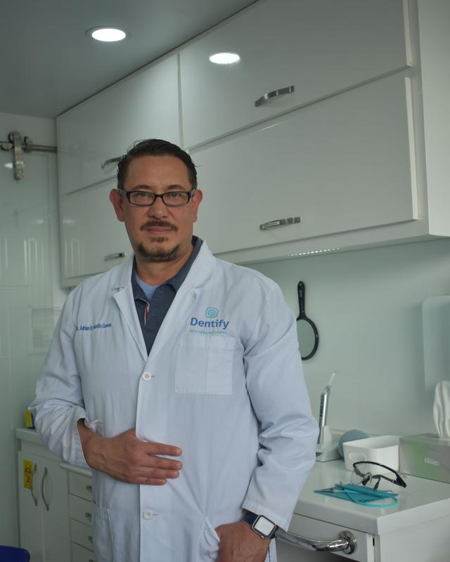 Male dentist in a white coat standing in a modern dental operatory