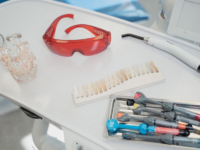 Dental tools and red safety glasses on a white tray