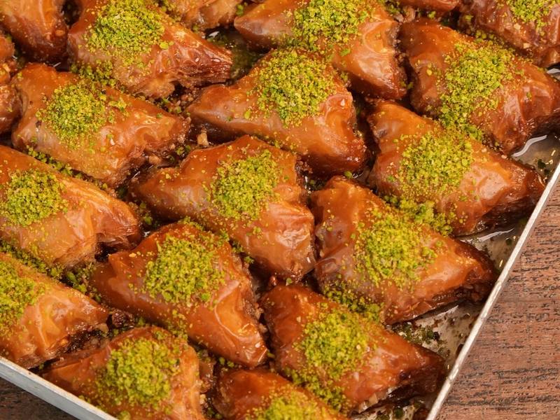 Tray of golden baklava pastries topped with crushed pistachios