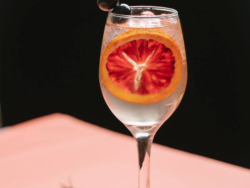 Spritz in a stemmed glass garnished with a slice of blood orange and rosemary