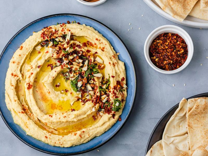 Bowl of hummus with olive oil, pita bread and a small dish of olive oil