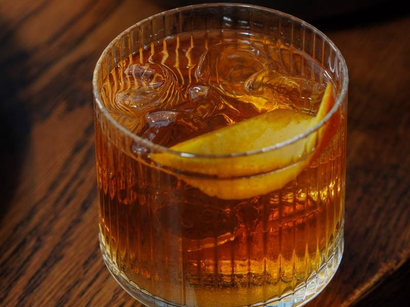 Old fashioned cocktail with ice and an orange peel in a rocks glass