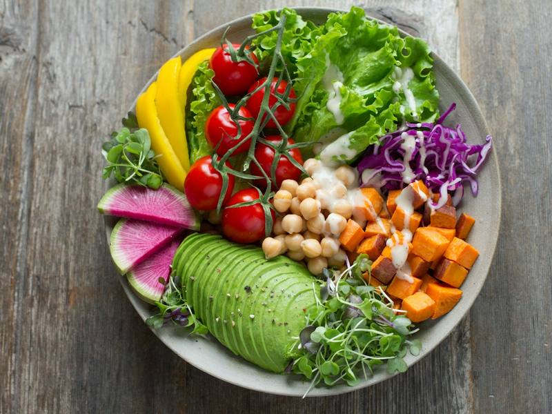 Colorful harvest bowl with avocado, chickpeas, radish, tomatoes and greens