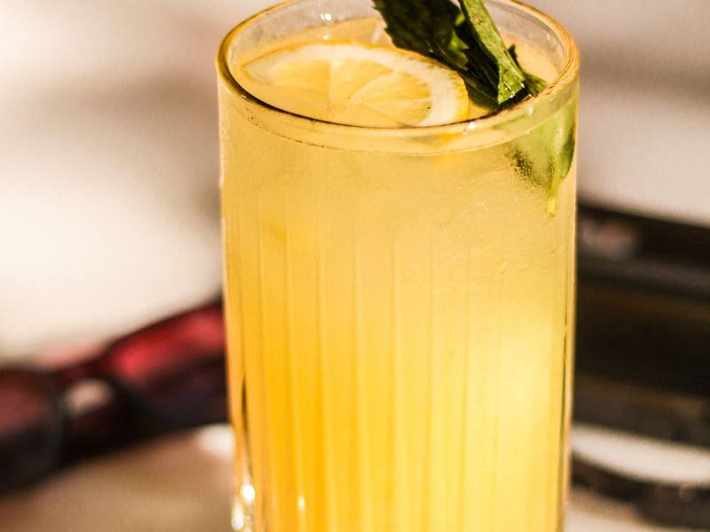 Tall glass of lemonade with a fresh mint leaf on a wooden table